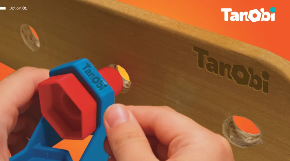 Hands tightening a red bolt and blue nut into a wooden Tanobi plank